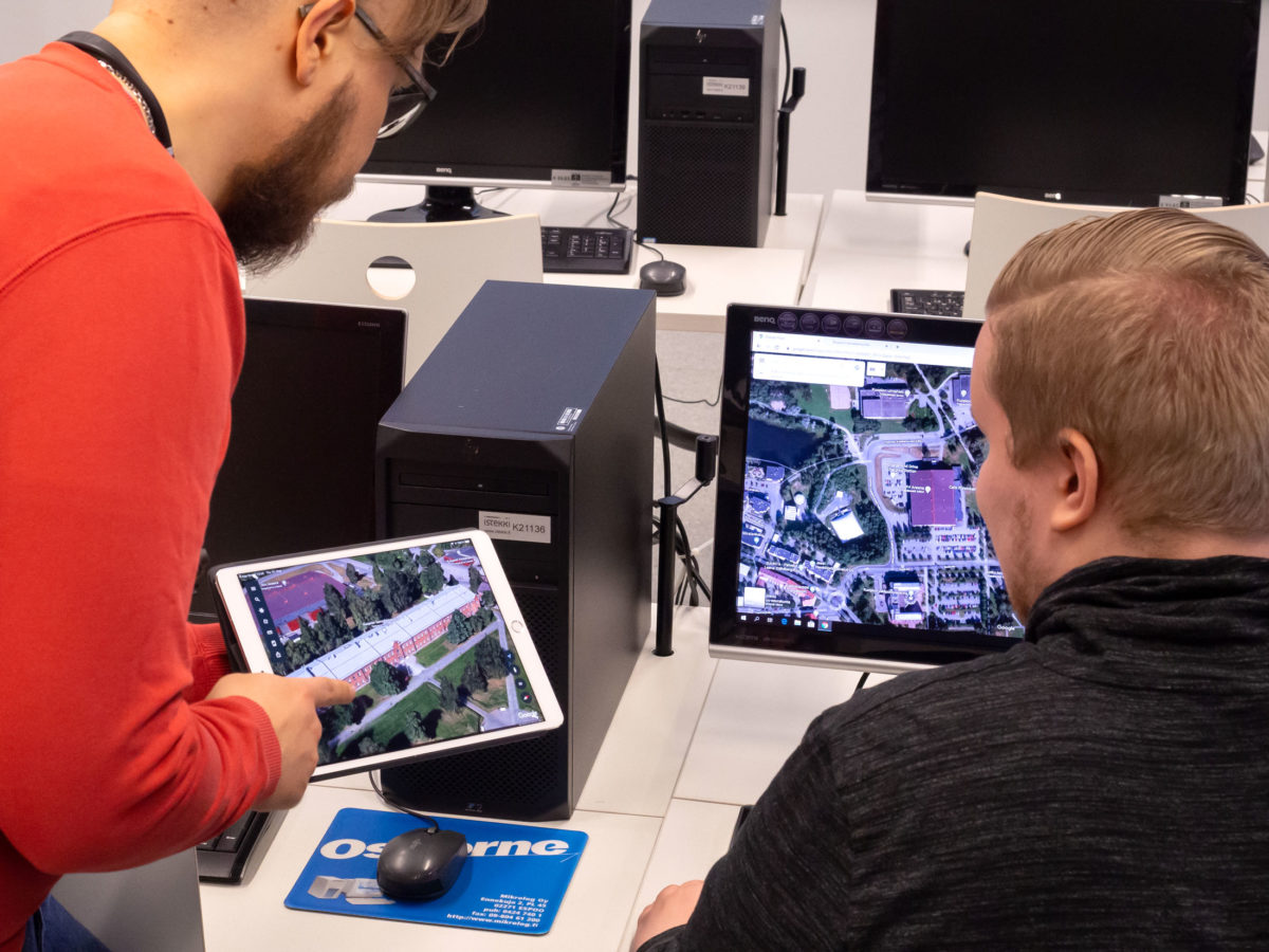Kuopion kansalaisopisto, tietotekniikkakursseja. Tietokoneluokassa opettaja näyttää oppilaalle iPadiltä kuvaa.