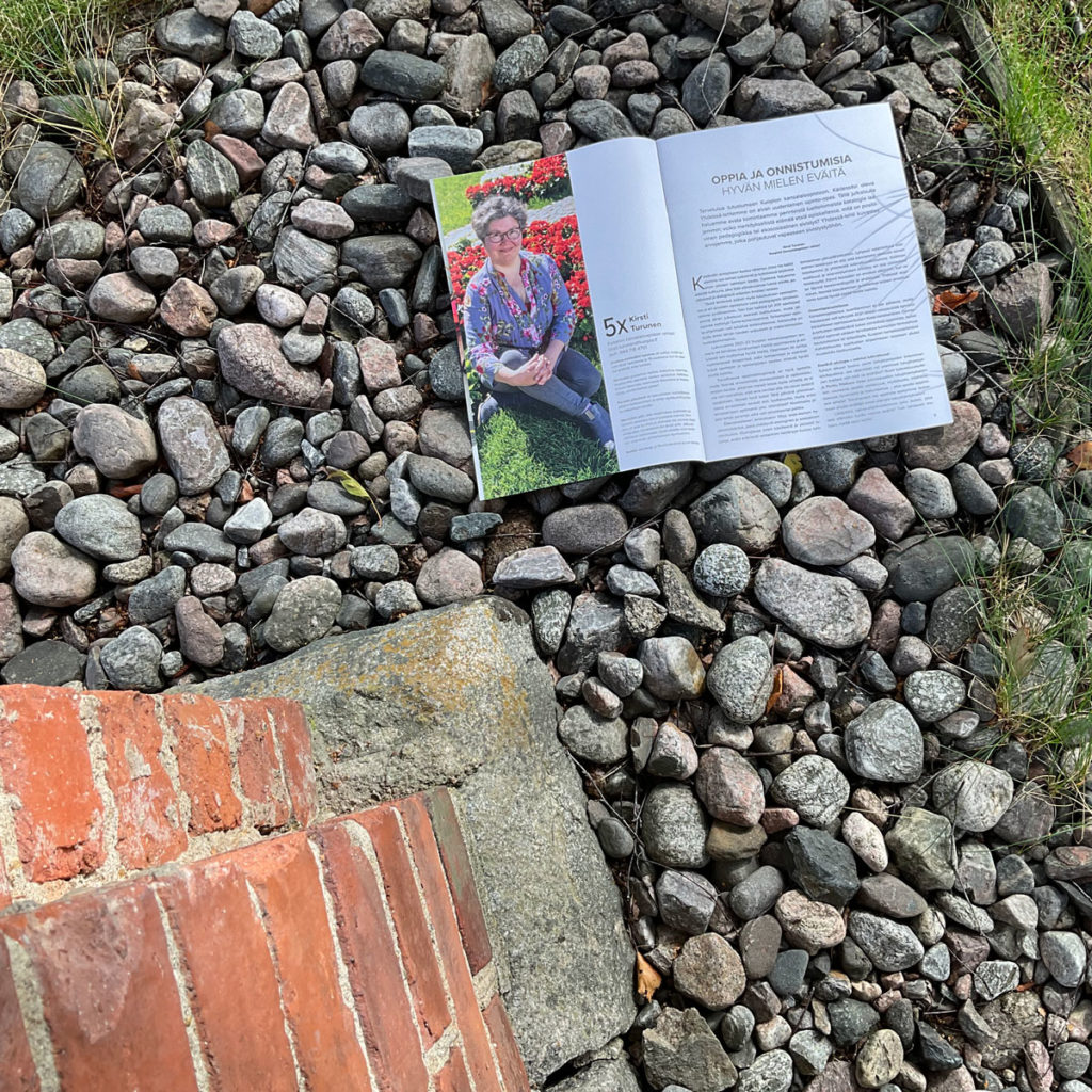 Yhdessä-lehden aukeama kuvattuna kivien päällä.